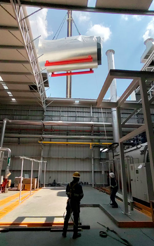 Our Project cargo industrial boiler being raised over the open ceiling of our client’s site. Nuestra carga sobredimensionada – el boiler industrial – siendo alzada a la planta de nuestro cliente por el techo abierto.