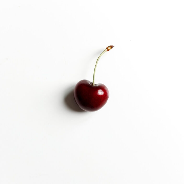 Picture of Nataliya Vaitkevich of a single cherry over a white background. Source: pexels.