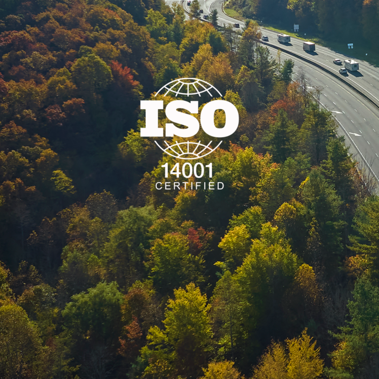 Over the picture of Woods by the side of a road with trucks, it is written ISO 14001